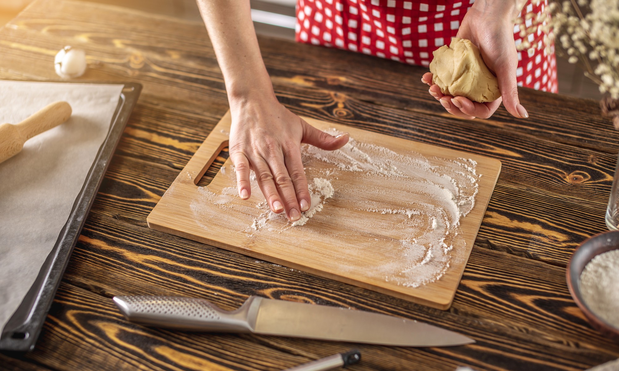 Hands kneading dough on wooden board